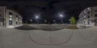 a fisheye lens view looking down a street at a skateboard park at night