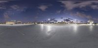 a skateboard park with an elevated area at night and a lot of people on the ground