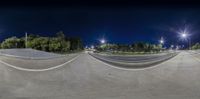 skateboarder doing a trick at night with lights behind him of trees and streetlights