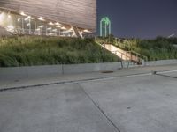 a person skateboard on a concrete surface near stairs in a park setting at night