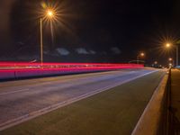 a road with multiple lights near the road and a sky line in the background and cars passing by