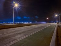 a road with multiple lights near the road and a sky line in the background and cars passing by