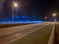 a road with multiple lights near the road and a sky line in the background and cars passing by