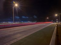 a road with multiple lights near the road and a sky line in the background and cars passing by