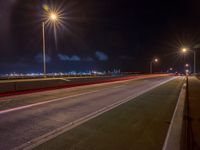 a road with multiple lights near the road and a sky line in the background and cars passing by