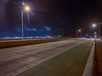 a road with multiple lights near the road and a sky line in the background and cars passing by