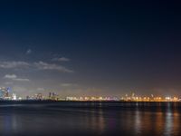 an airplane flies over the city on the ocean at night, with bright light and clouds