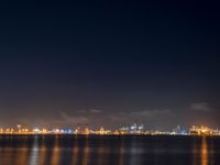 an airplane flies over the city on the ocean at night, with bright light and clouds