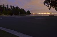 an empty road in the foreground, with a river running through the background at night