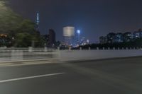 a city street with buildings and neon lights at night time in hong china as seen from an empty city highway