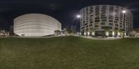 a street with grass and buildings at night time in view from the ground level of the image