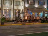 people sit outside a restaurant in the city at night time with no traffic on the road