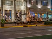 people sit outside a restaurant in the city at night time with no traffic on the road