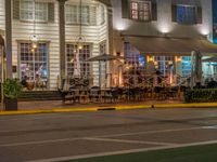 people sit outside a restaurant in the city at night time with no traffic on the road