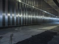 a person walking on a street at night with their skateboard and in an area full of shiny metal