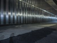 a person walking on a street at night with their skateboard and in an area full of shiny metal