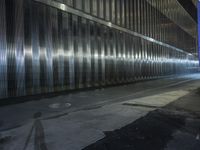 a person walking on a street at night with their skateboard and in an area full of shiny metal