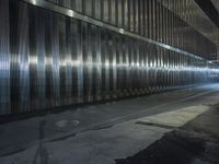 a person walking on a street at night with their skateboard and in an area full of shiny metal