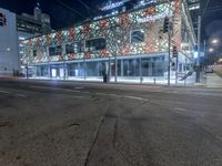 an empty street near a building at night with no traffic lights in the foreground