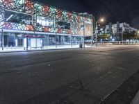 an empty street near a building at night with no traffic lights in the foreground