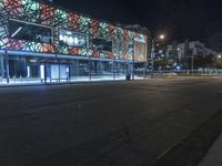 an empty street near a building at night with no traffic lights in the foreground
