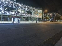 an empty street near a building at night with no traffic lights in the foreground