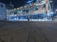 an empty street near a building at night with no traffic lights in the foreground