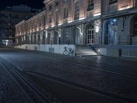 a night time image of a man on a bicycle on the street in front of a building