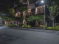 night shot on city street in urban setting with residential apartment building and trees beside it