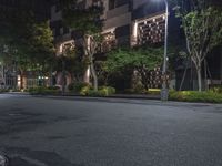 night shot on city street in urban setting with residential apartment building and trees beside it