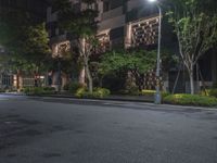 night shot on city street in urban setting with residential apartment building and trees beside it