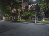 night shot on city street in urban setting with residential apartment building and trees beside it