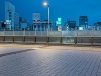 people standing on a subway platform with many buildings in the background at night light in tokyo