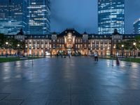 the sky is very cloudy above the city buildings at night, with people walking in front of it