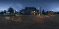 the intersection of a parking lot and an office building at night with street light and dark clouds in the background