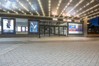 a building with a brick facade at night in front of a theater door with lights on it