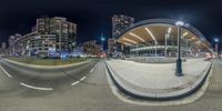 this fish eye lens is shown on a street corner at night with a light and buildings