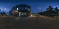 a street view looking up at a road corner with lights in the background and building to the left