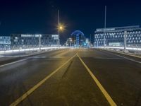 a long street is empty with cars on it at night, which is full of buildings