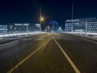 a long street is empty with cars on it at night, which is full of buildings