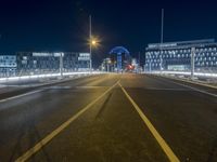 a long street is empty with cars on it at night, which is full of buildings