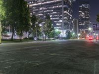 traffic drives down a deserted city street at night time with tall skyscrapers in the background