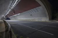 a highway leading into an open and empty tunnel on a windy day with lights shining on