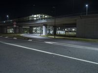 an empty parking lot and street underpass at night, lit up with street lights