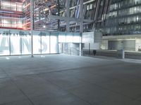 an outdoor space features glass walls and columns at night, with light streaming through the glass walls