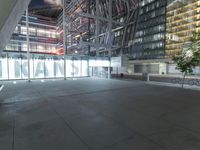 an outdoor space features glass walls and columns at night, with light streaming through the glass walls