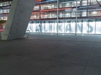 an outdoor space features glass walls and columns at night, with light streaming through the glass walls