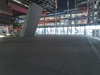 an outdoor space features glass walls and columns at night, with light streaming through the glass walls