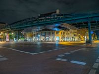 the empty street is filled with people walking and biking under an overpass at night