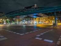 the empty street is filled with people walking and biking under an overpass at night